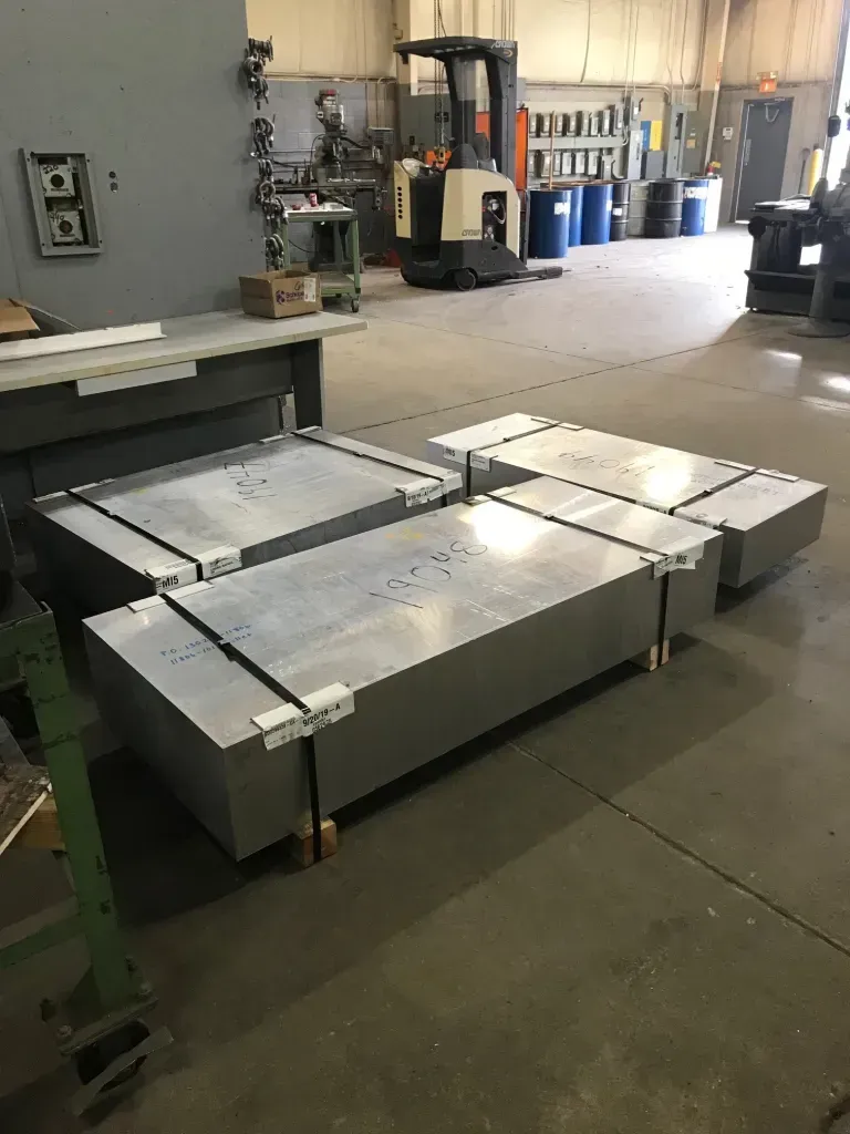 Industrial workshop with large metal tables and a forklift in the background