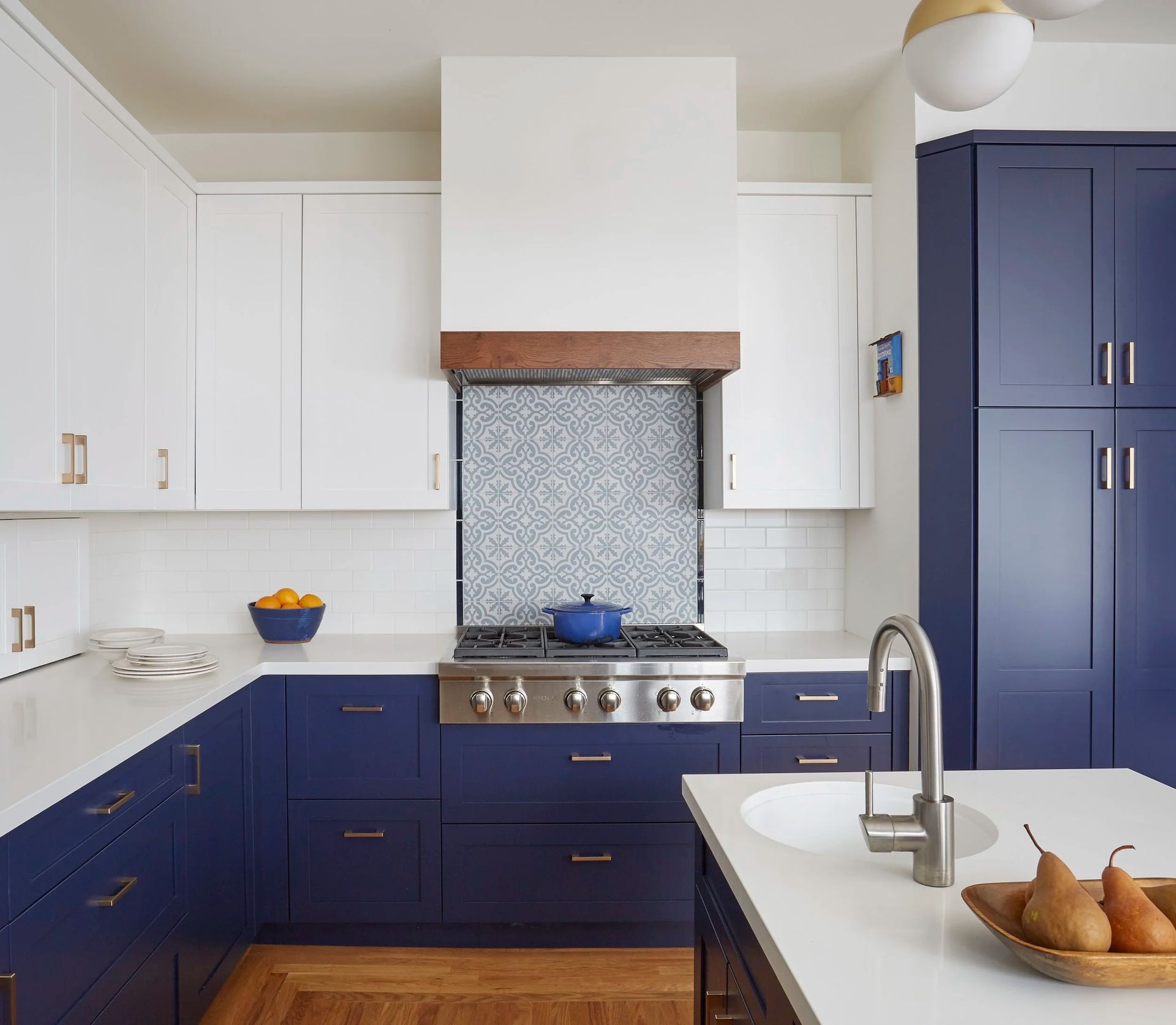 Blue and white kitchen with stove and island, a blue pot, and fruit.