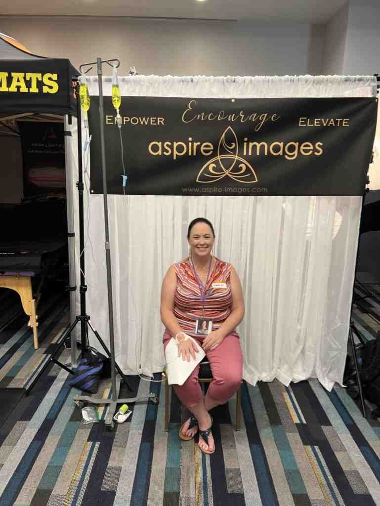 A woman is sitting in front of a sign that says aspire images.
