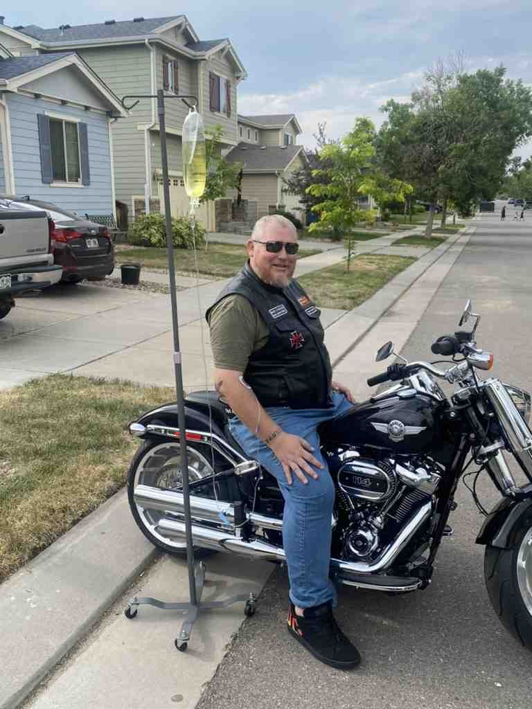 A man is sitting on a motorcycle next to an iv pole.