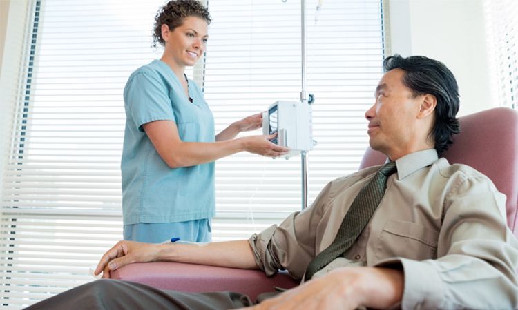 a man is sitting in a hospital chair getting an IV from a nurse