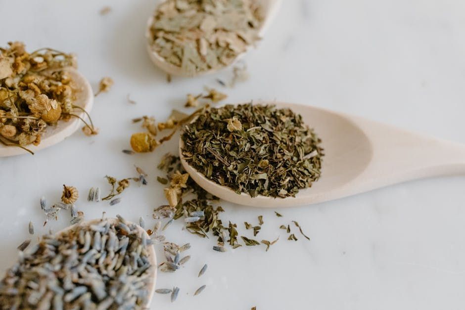 A wooden spoon filled with dried herbs on a table.
