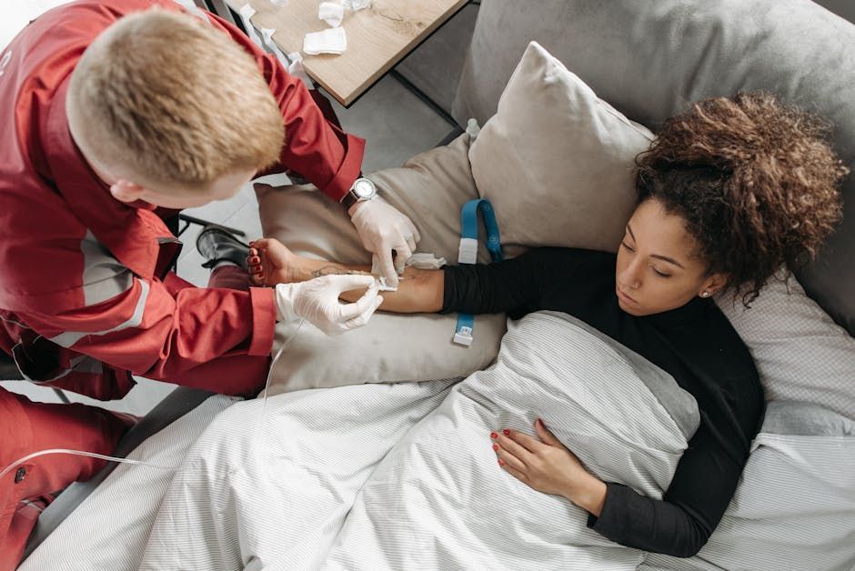A woman is laying on a couch getting an injection in her arm.