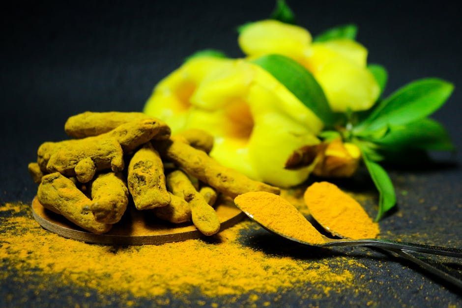 There is a spoon of turmeric next to a pile of turmeric.