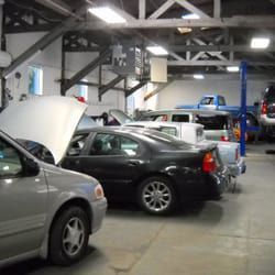 Auto repair shop with several parked cars and one hood open inside a garage | Marin Automotive