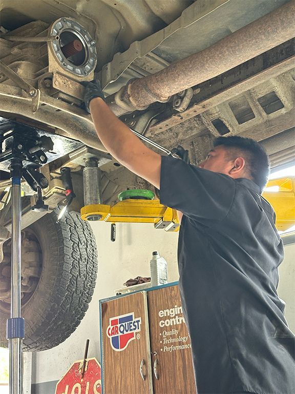 Mechanic inspecting the underside of a lifted vehicle in an auto repair shop | Marin Automotive
