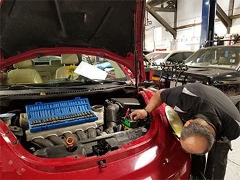 Mechanic inspecting a red car’s engine bay in an auto repair shop | Marin Automotive