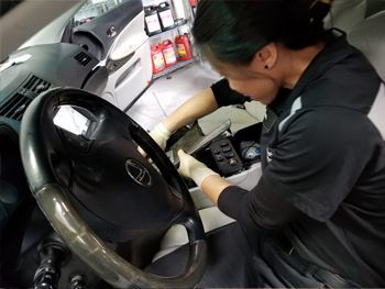 Mechanic working on a car dashboard with tools in the driver’s seat area | Marin Automotive