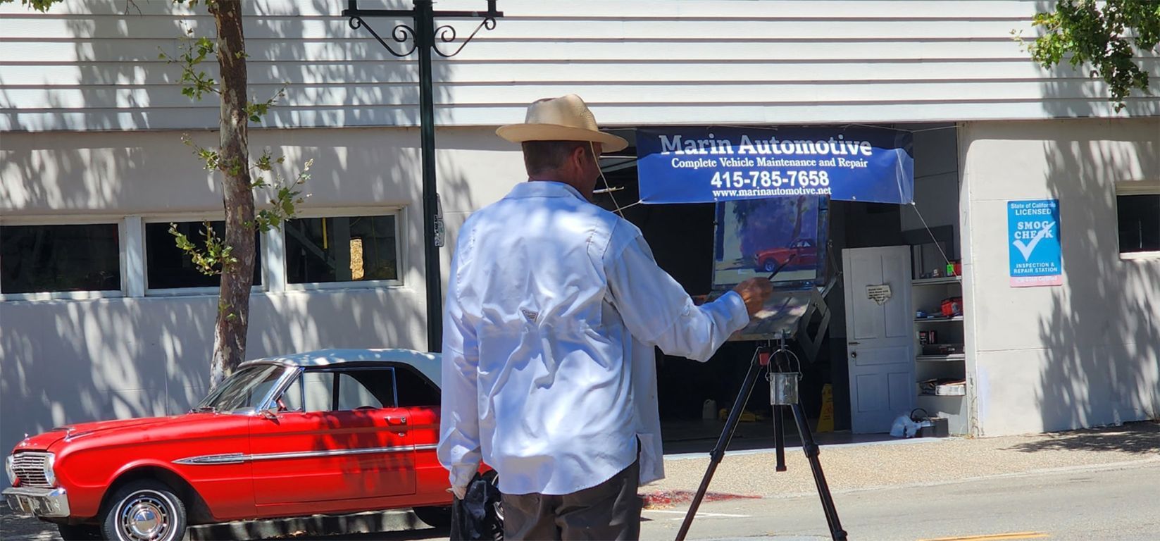 Person filming a red vintage car outside a storefront with a blue awning | Marin Automotive