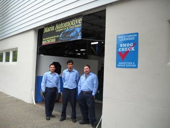 Three mechanics standing outside an auto repair shop with a blue Smog Check sign. | Marin Automotive
