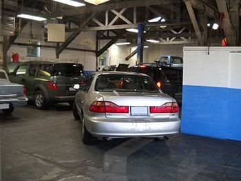 Cars parked inside an industrial garage or warehouse, including a silver sedan in the foreground. | Marin Automotive
