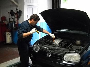 Mechanic inspecting a black Volkswagen engine in a garage with the hood open | Marin Automotive