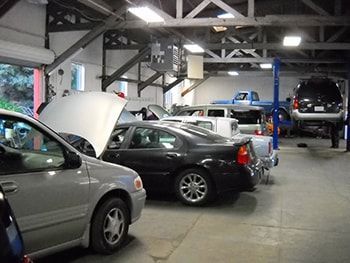 Cars parked inside an auto repair garage, including one with its hood open | Marin Automotive