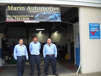 Three men in blue shirts stand outside Marin Automotive auto repair shop entrance. | Marin Automotive