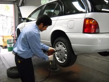 Mechanic inflating a silver SUV tire in a garage | Marin Automotive