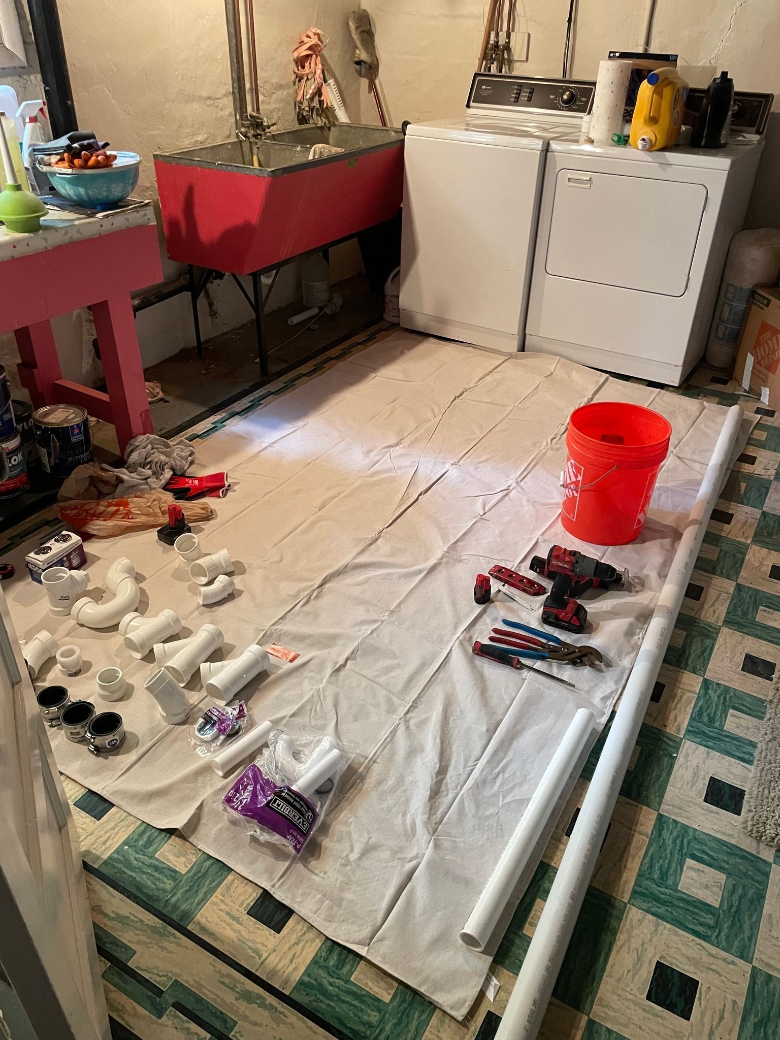 A laundry room with a red bucket and tools on the floor.
