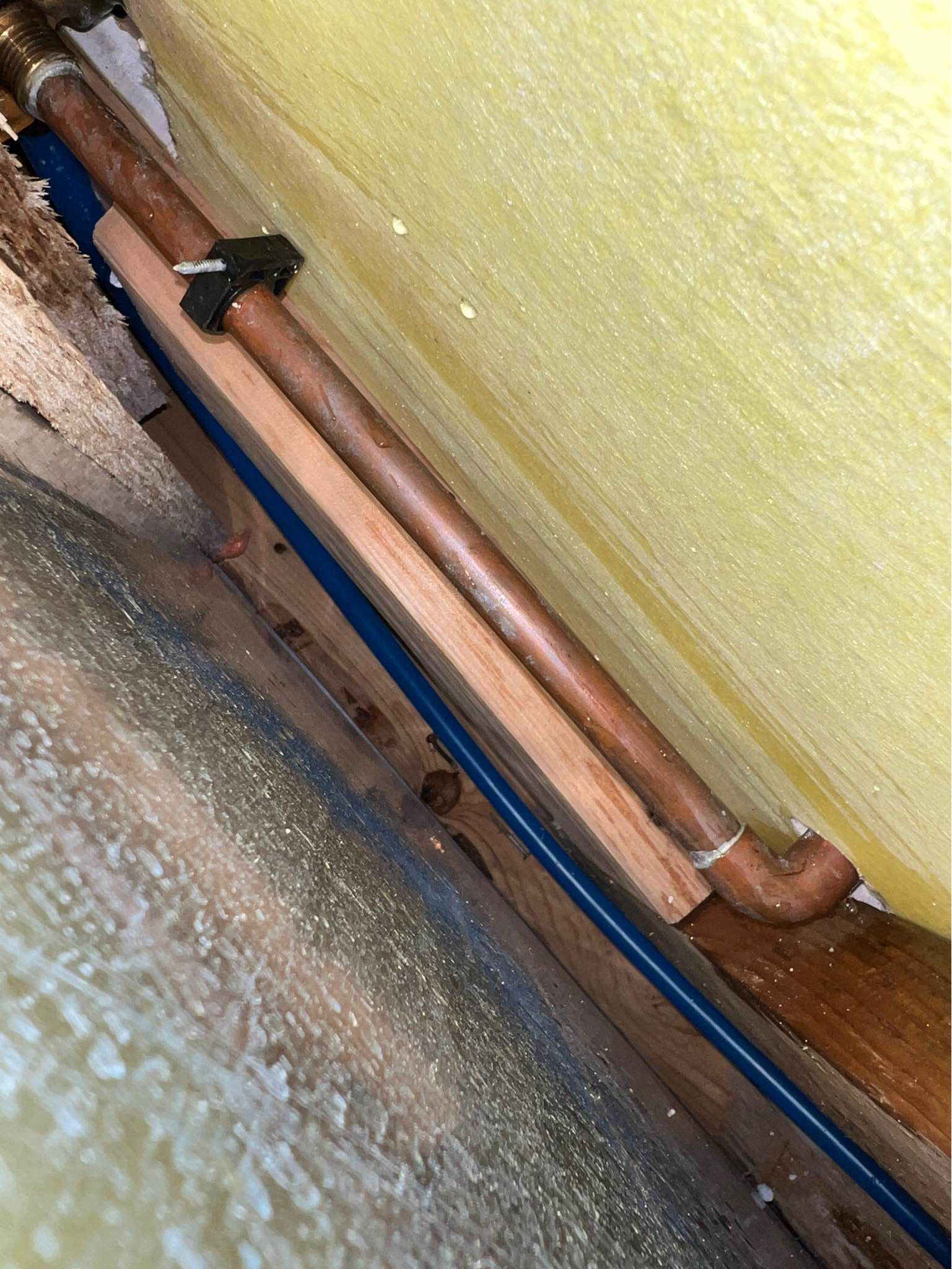 A close up of a copper pipe with a blue hose attached to it.
