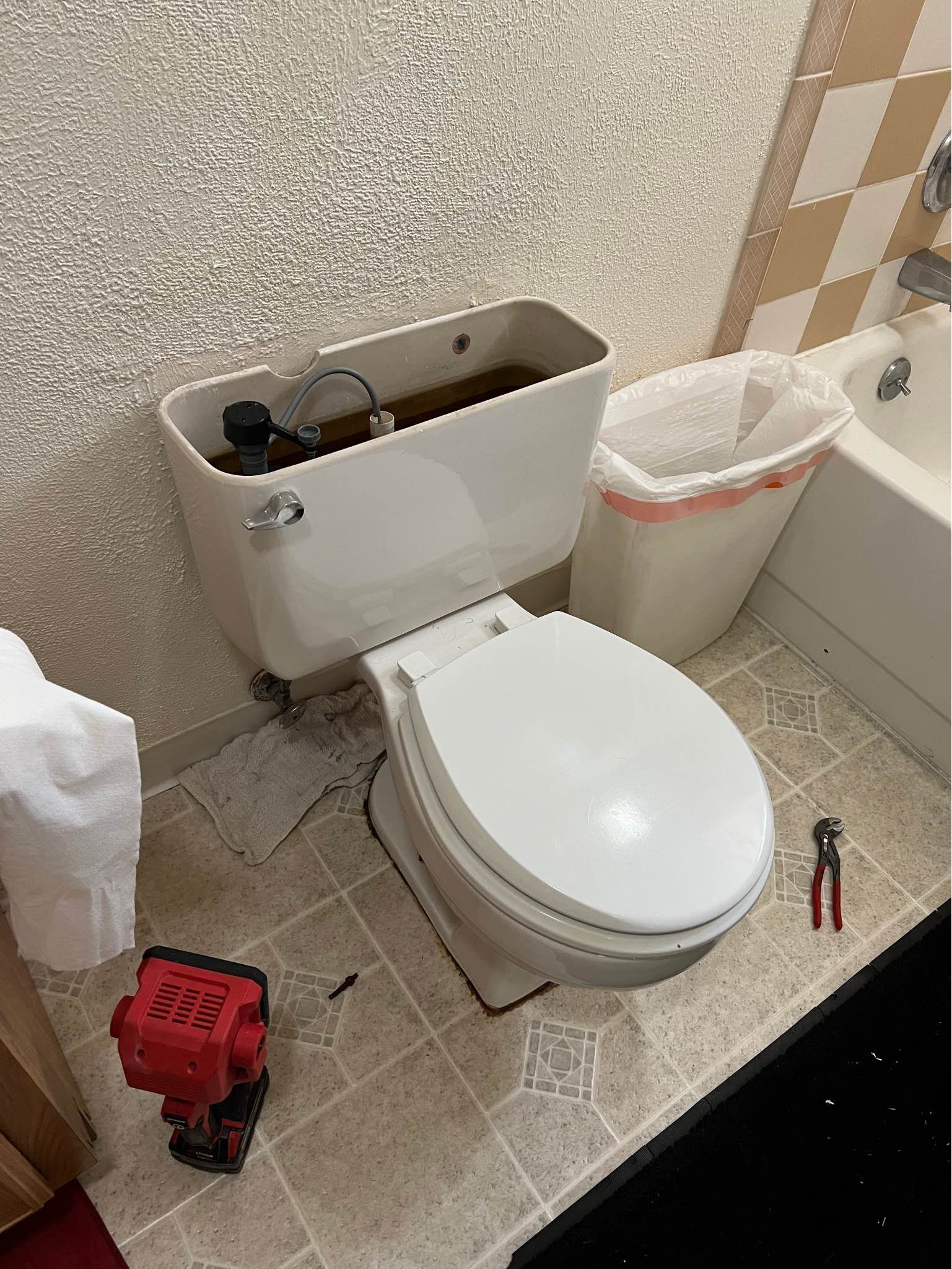A toilet is sitting in a bathroom next to a bathtub.