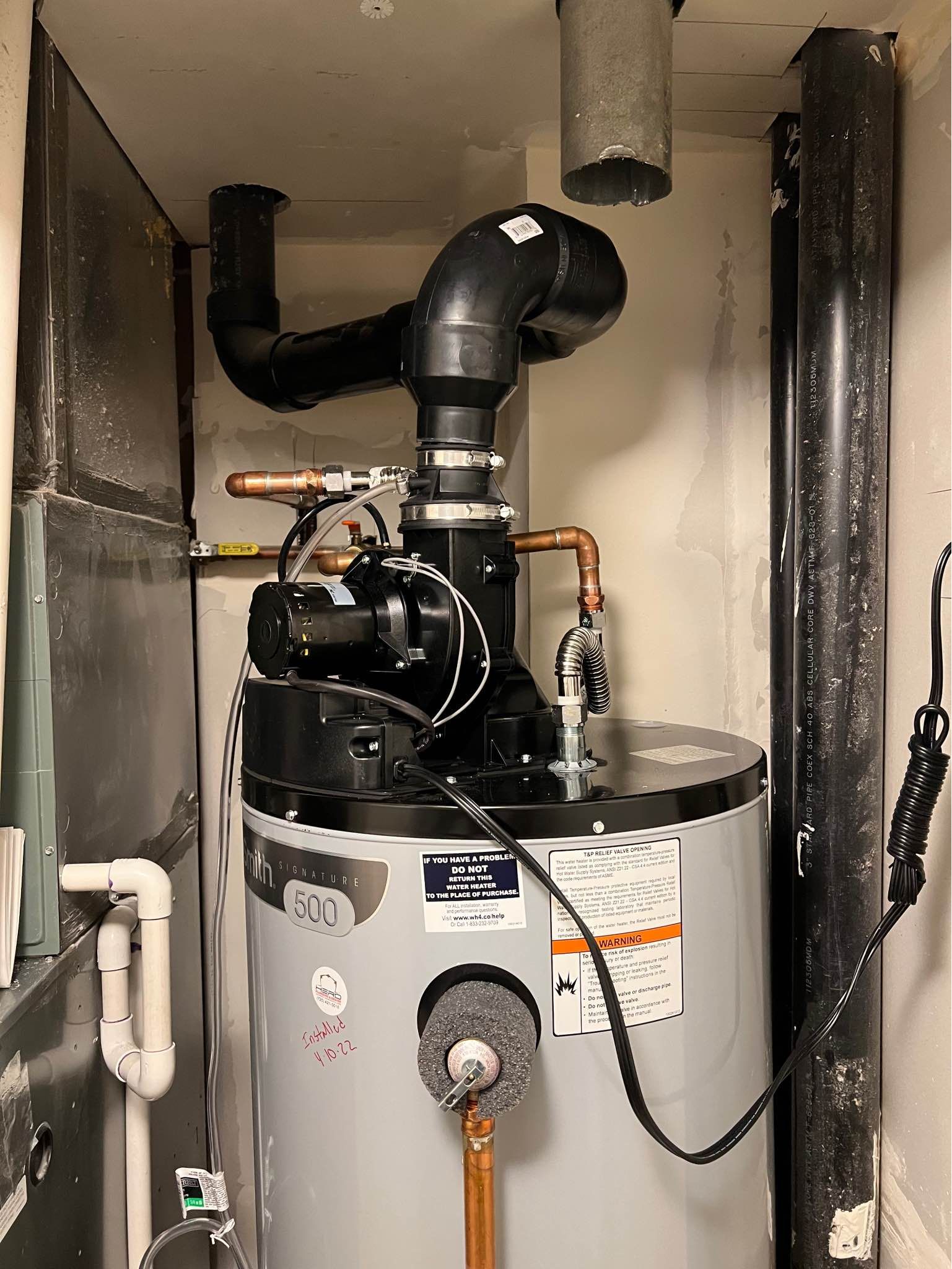 A water heater is sitting in a room next to a pipe.