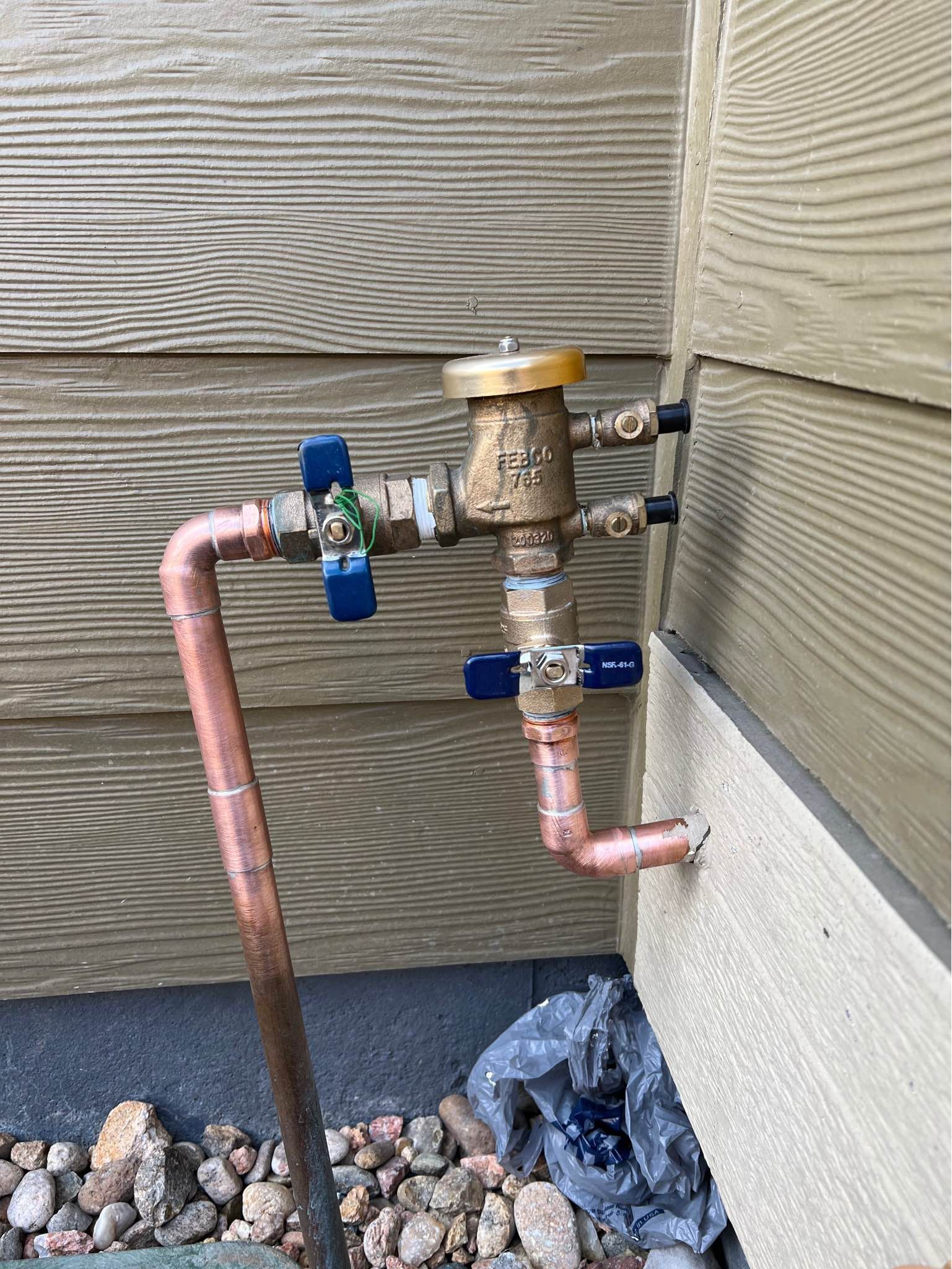 A copper pipe is attached to the side of a house.