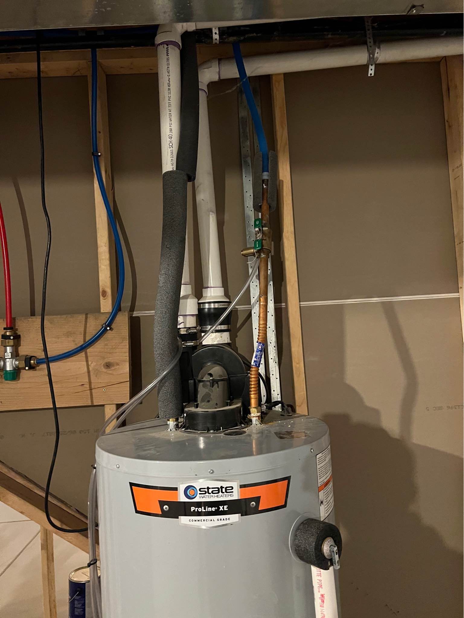 A water heater is hanging from the ceiling in a basement.