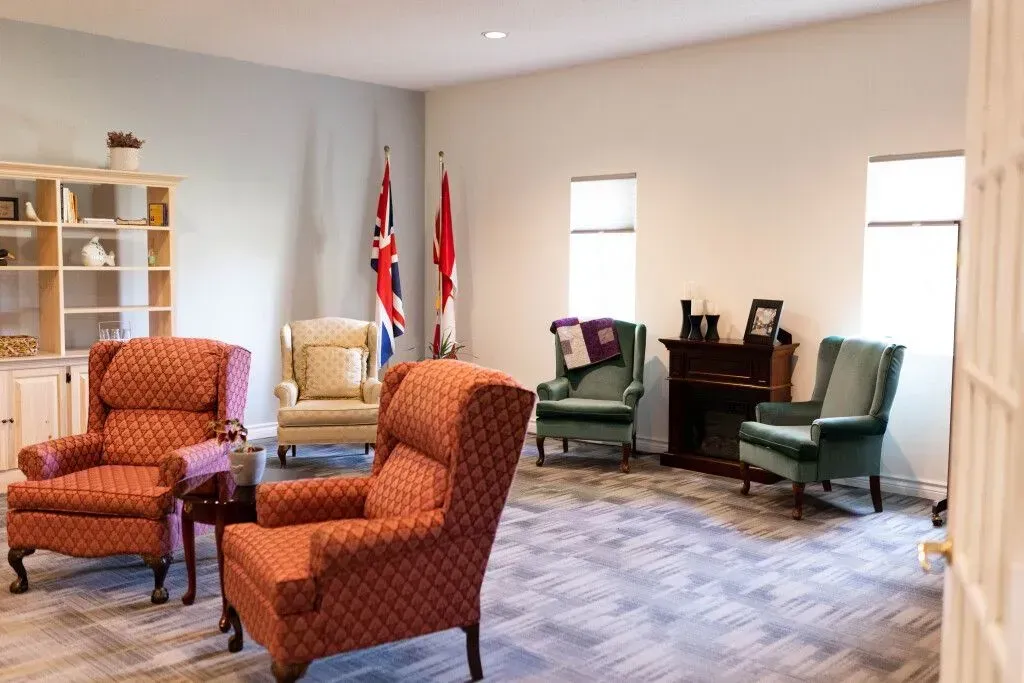 Formal sitting room with patterned armchairs, flags, and green chairs by a bright window