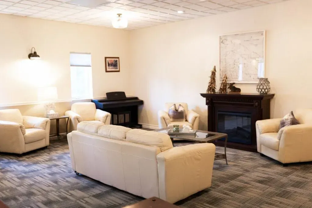 Bright living room with cream sofas, black piano, and fireplace on patterned carpet.