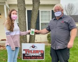 A man and a woman wearing face masks are standing in front of a house.