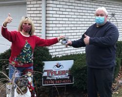A man and a woman wearing face masks are standing in front of a brick building.