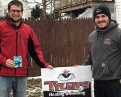 Two men are standing next to each other holding a sign for tyler 's heating and cooling.