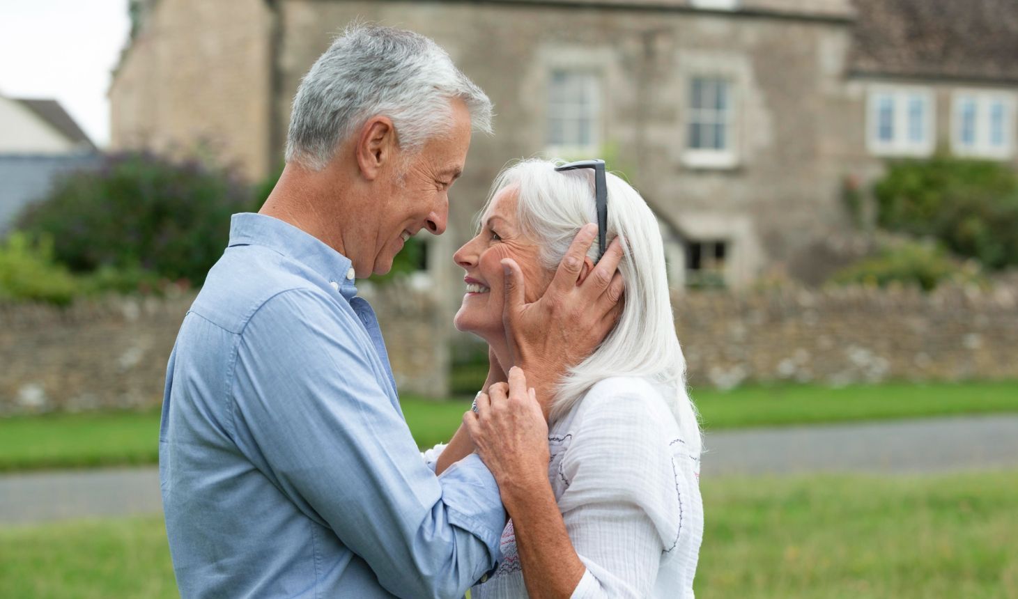 A man and a woman are hugging each other in front of a house.