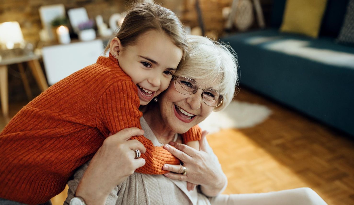 A little girl is hugging an older woman in a living room.