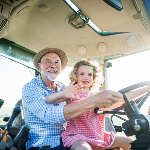 A man and a little girl are sitting in a tractor