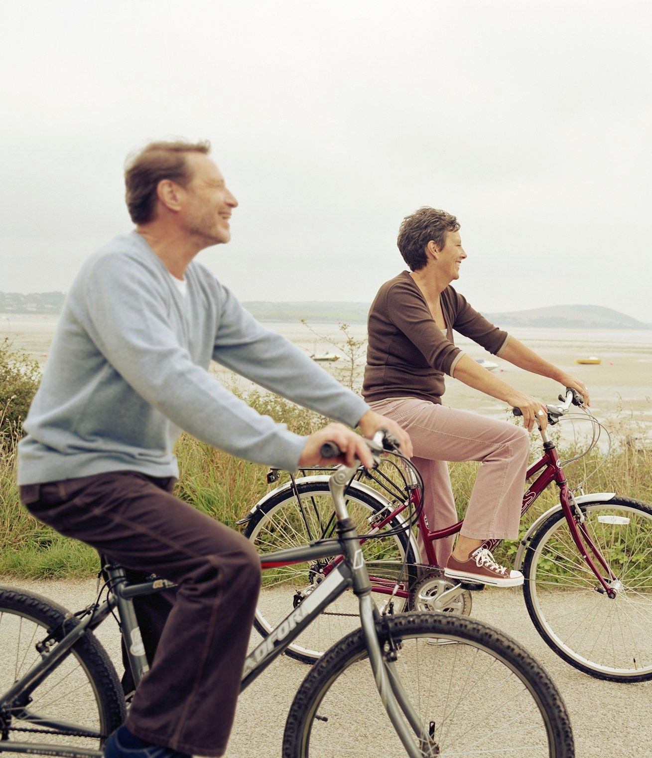 A man and a woman are riding bicycles on a path