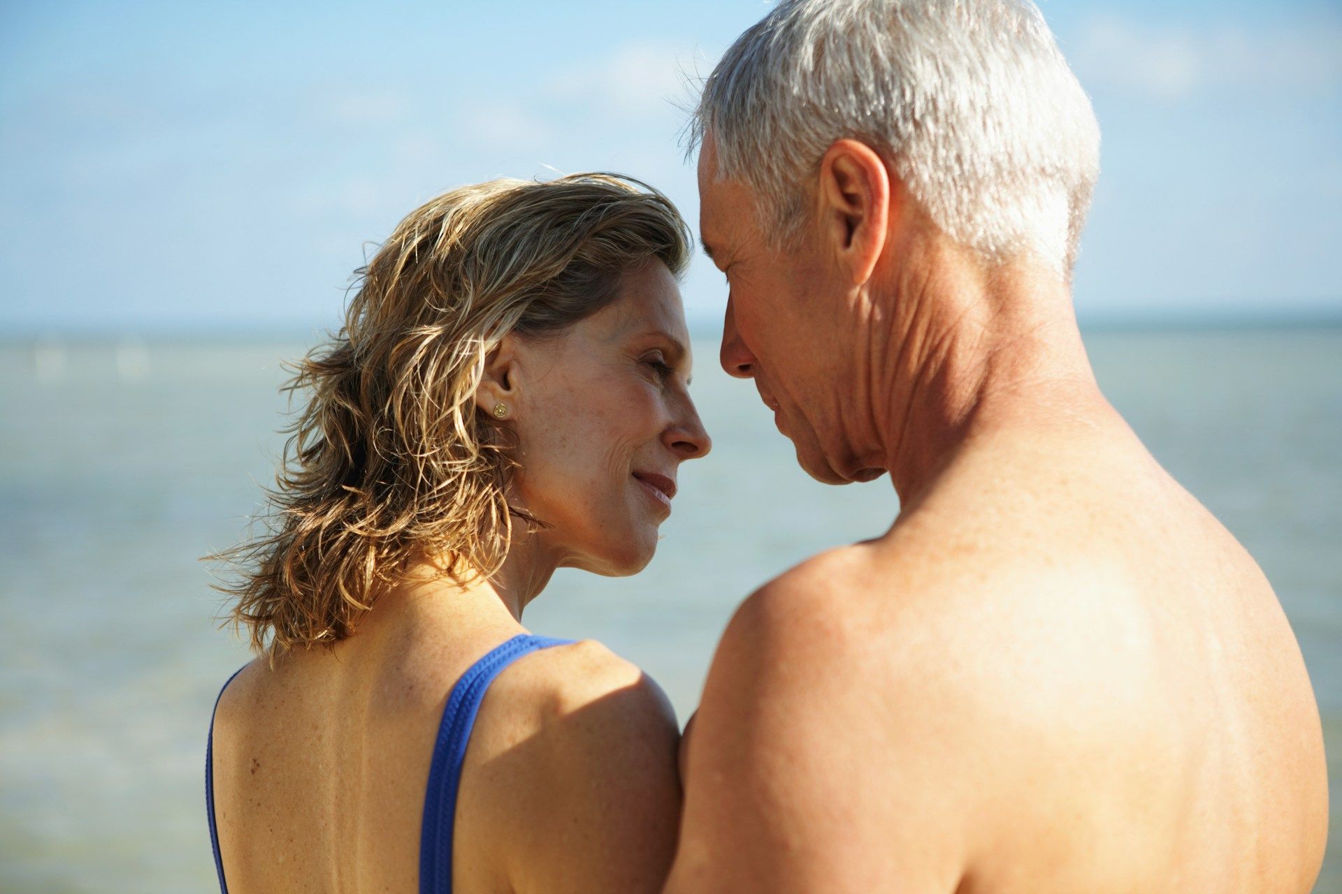 A man and a woman are looking at each other on the beach.
