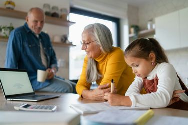 A little girl is sitting at a table with her grandparents.