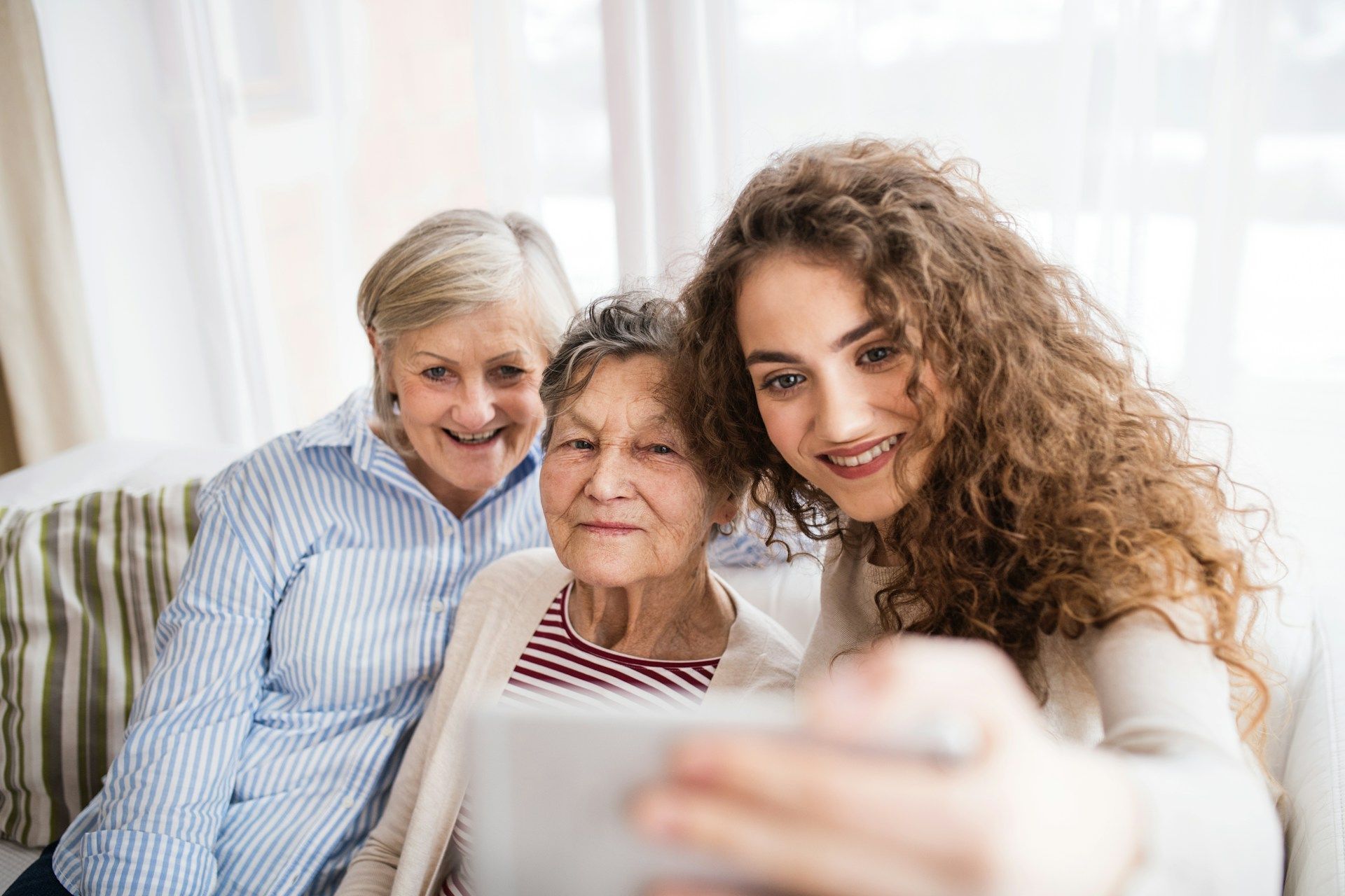A young woman is taking a selfie with two older women.
