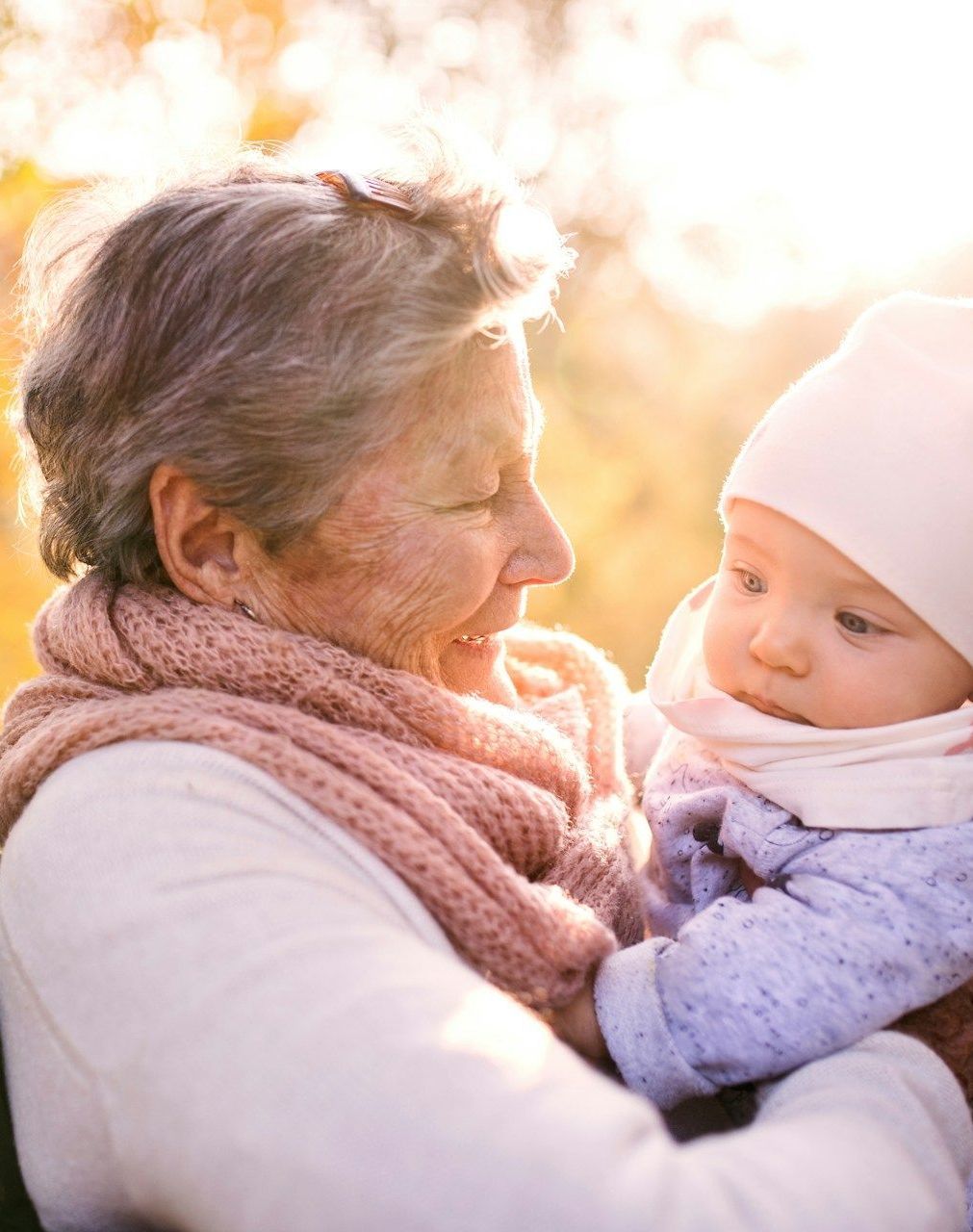 An elderly woman is holding a baby in her arms.