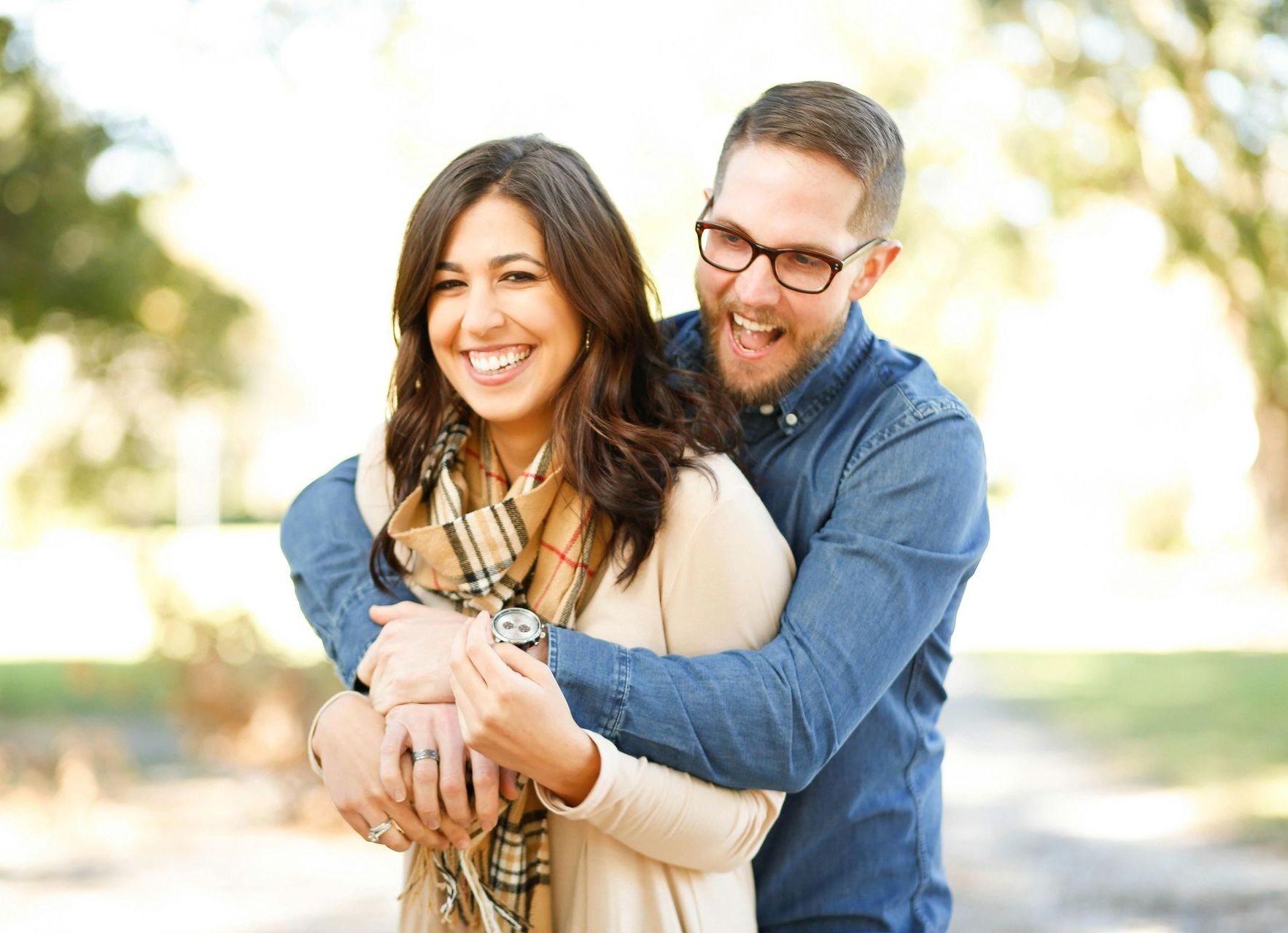 A man is hugging a woman in a park.