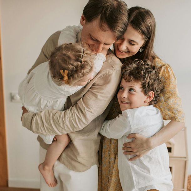 A man and woman are holding two children and smiling.