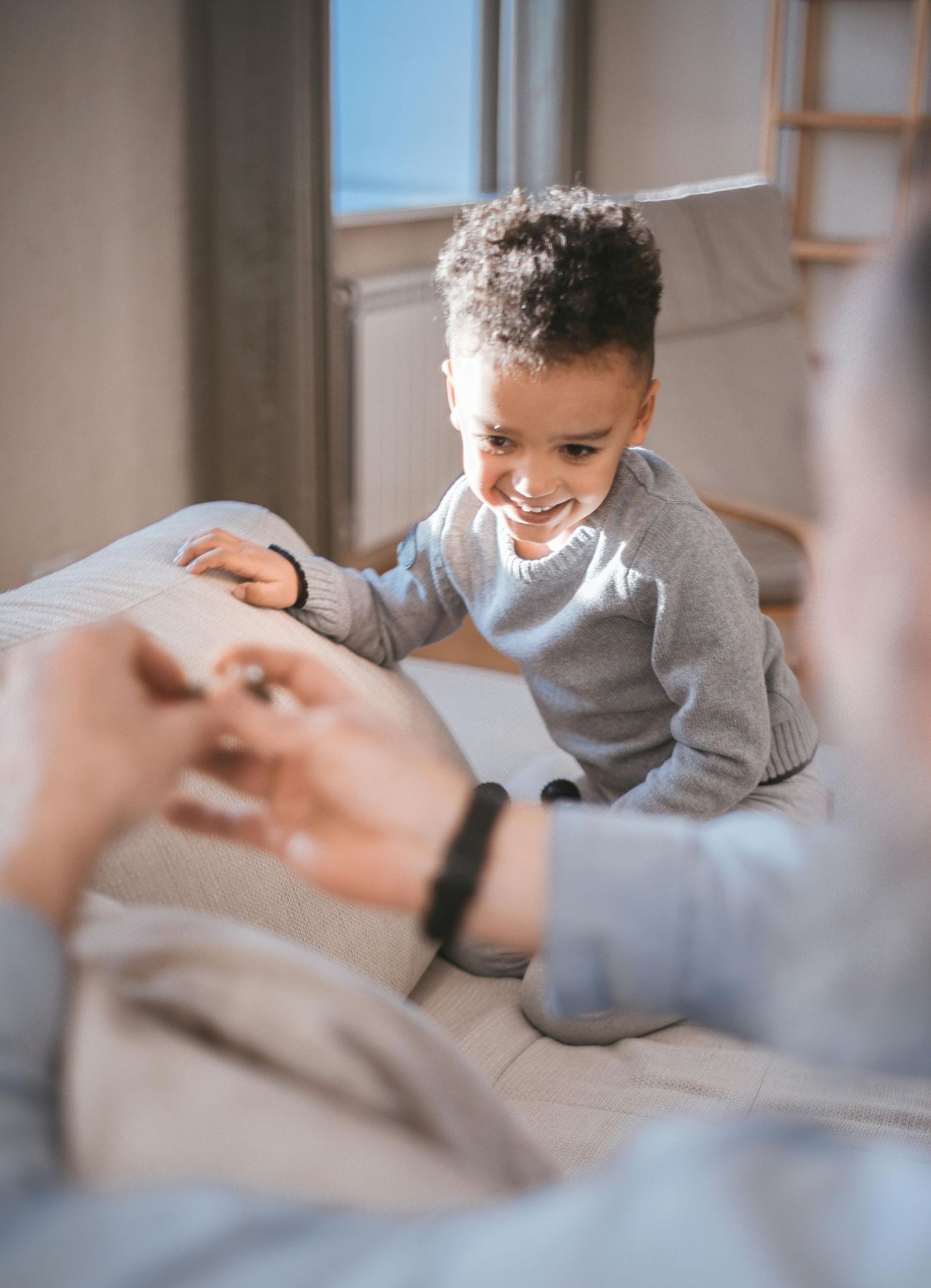 A little boy is sitting on a couch playing with a man.
