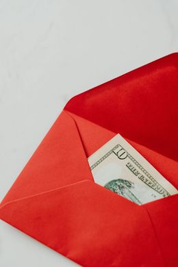 Red envelope with a dollar bill partially tucked inside on a light background