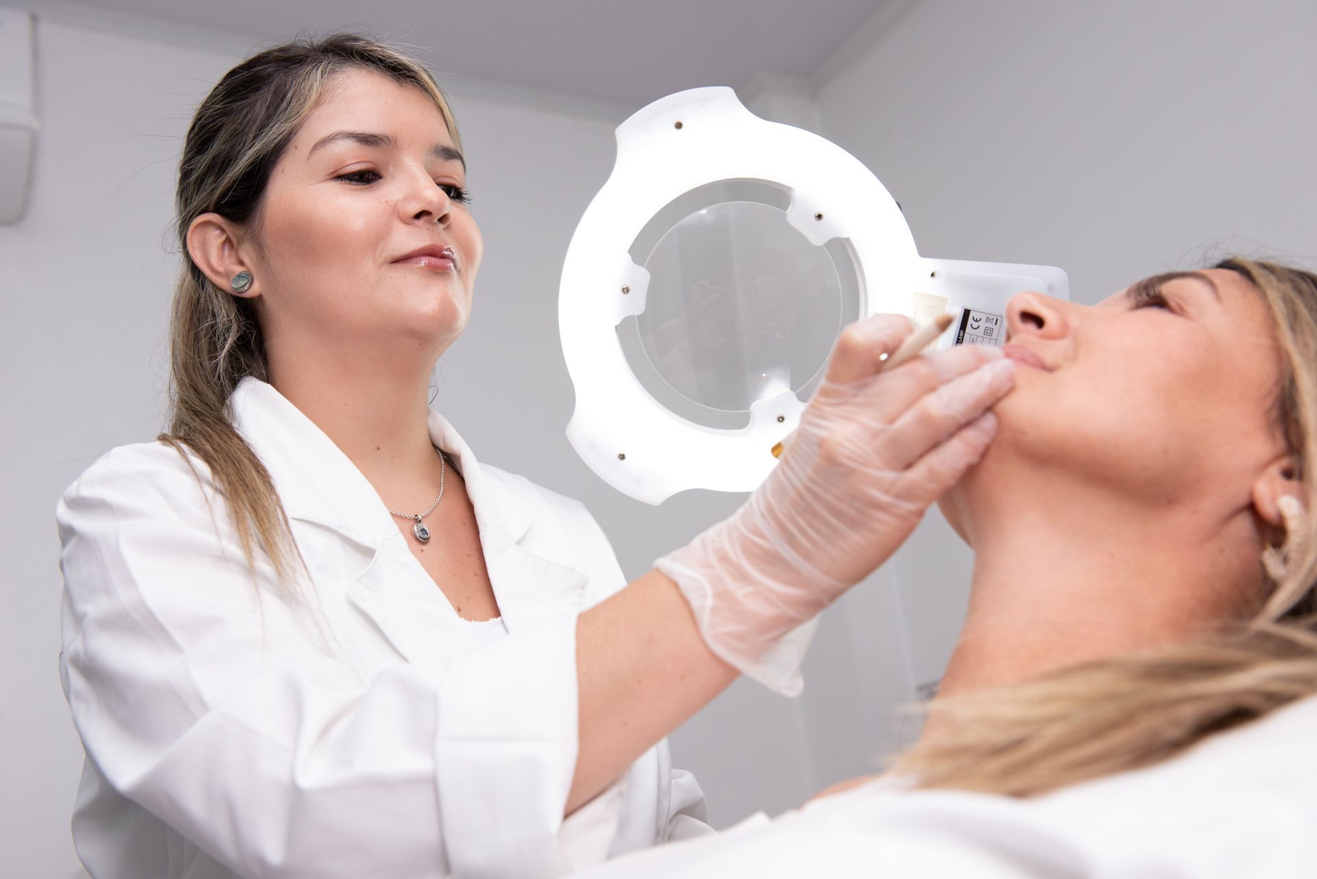 Una doctora examina el rostro de una mujer con una lupa.
