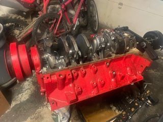 Red engine block and crankshaft assembly on a garage floor.