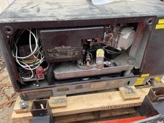 Black generator with open panel, revealing internal components and wiring.