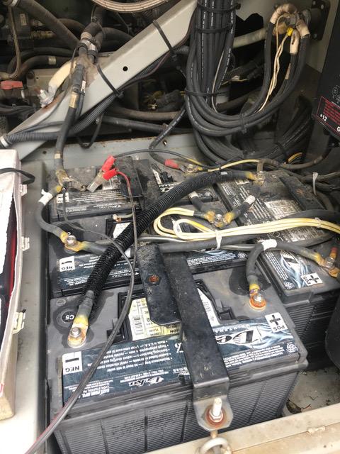 Batteries in a vehicle, likely for electrical power. Black batteries are connected with cables in a compartment.