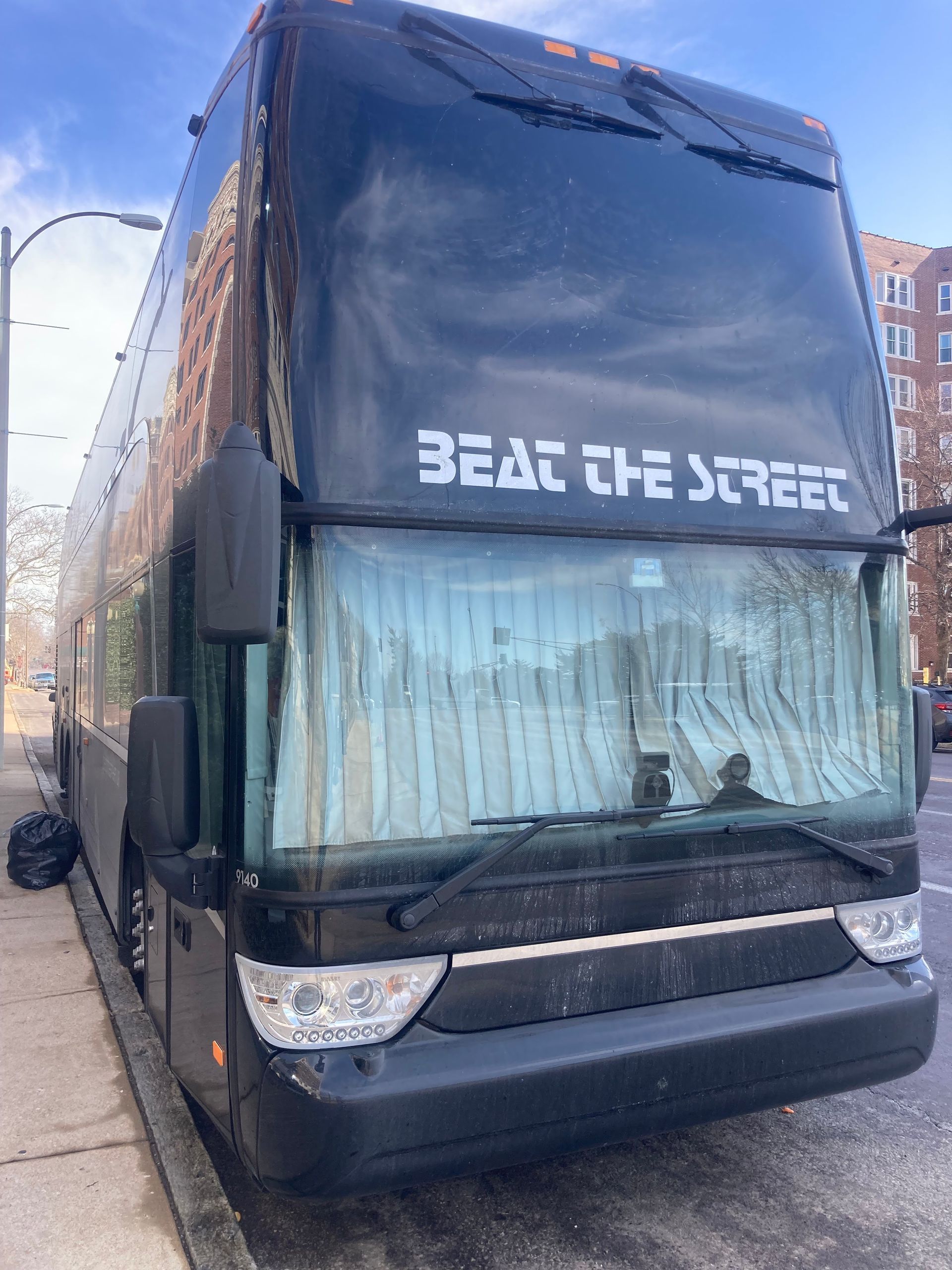 Black double-decker bus parked on a city street; text 