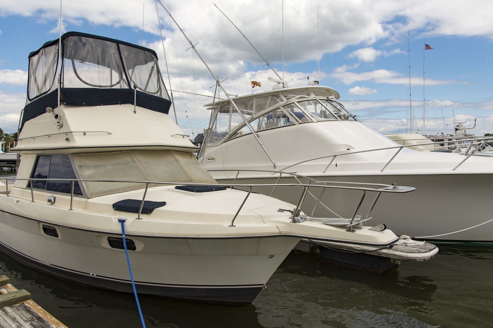 Two white motorboats docked on a sunny day with a cloudy sky in the background.