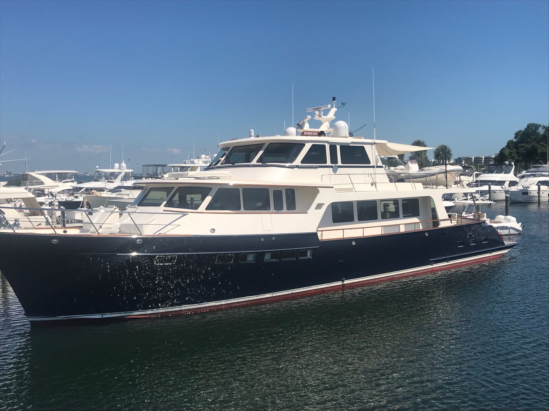 A blue and white yacht docked at a marina on a sunny day.