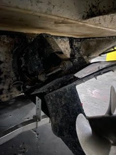 Underside of a boat showing a dark-colored propeller and drive system, with a bracket and hull visible.